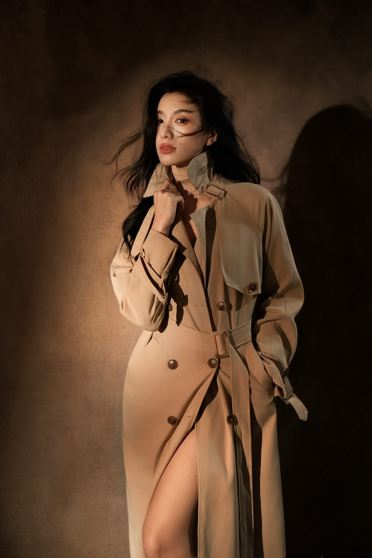 K9 Studio client portrait in a beige trench coat, moody warm-toned studio lighting