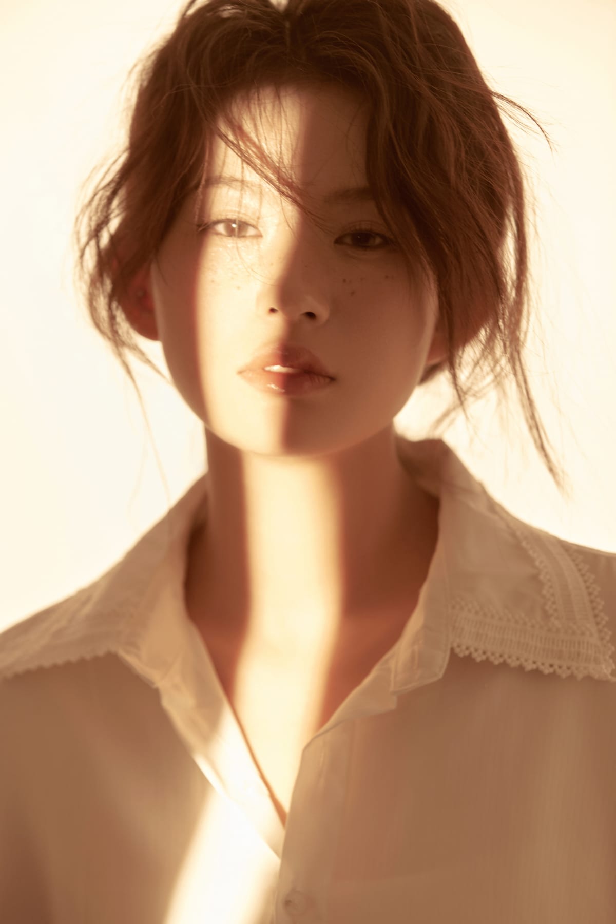 K9 Studio client portrait in a white lace-collar shirt, warm backlit sunbeam across the face