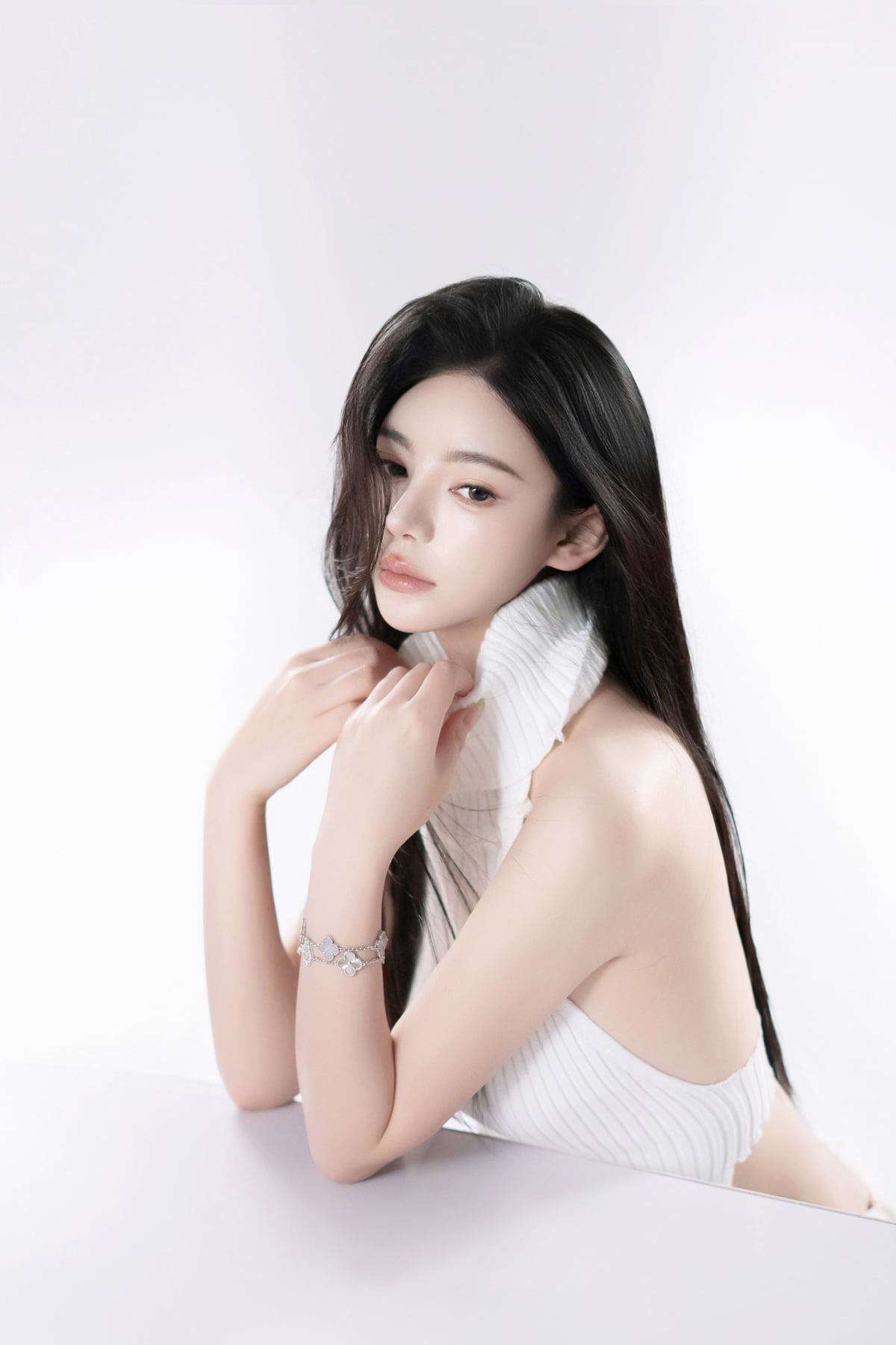 K9 Studio client portrait in a white ribbed turtleneck, hands clasped at the neck, plain white background