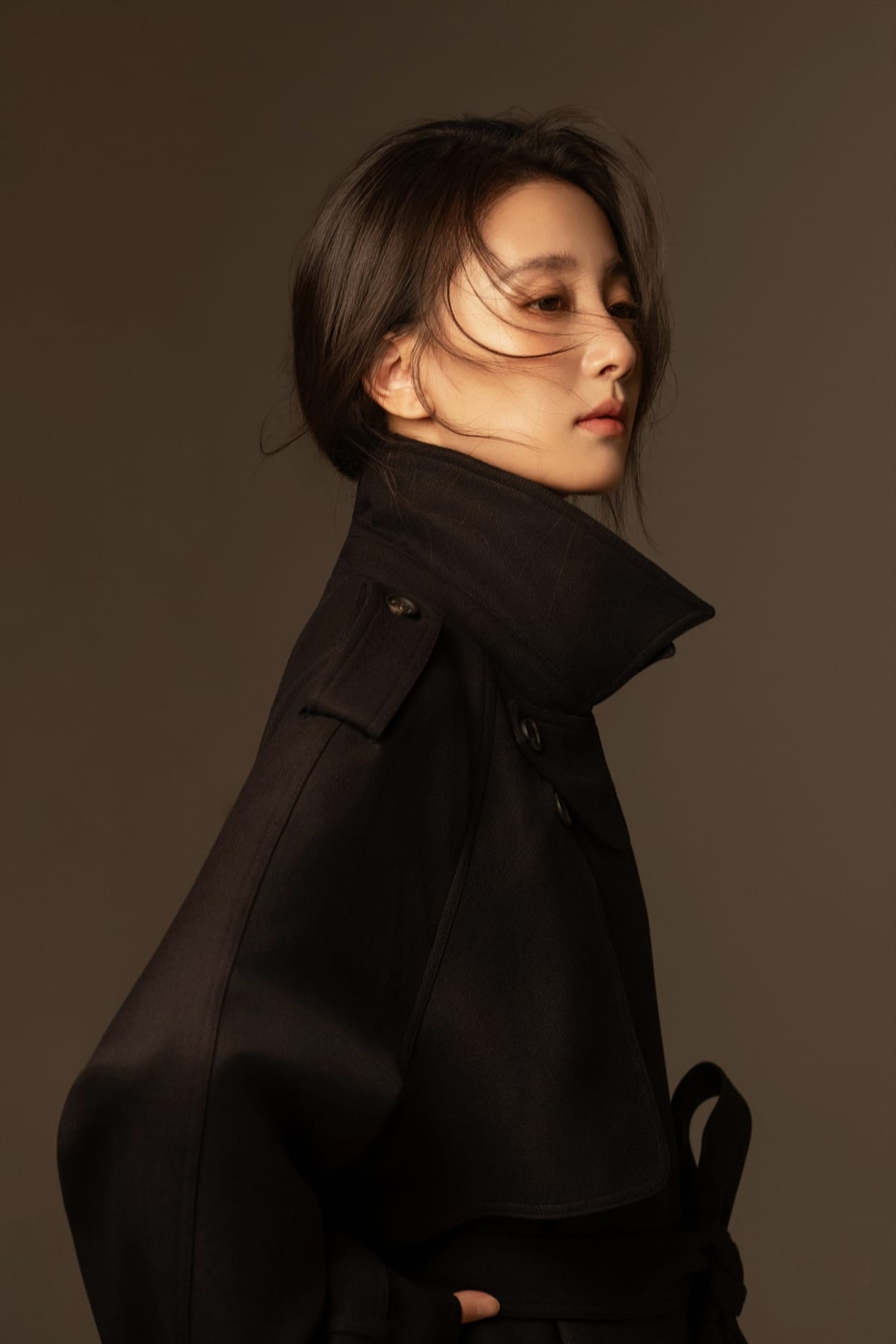K9 Studio client portrait in a black structured coat, warm rim lighting, profile turn