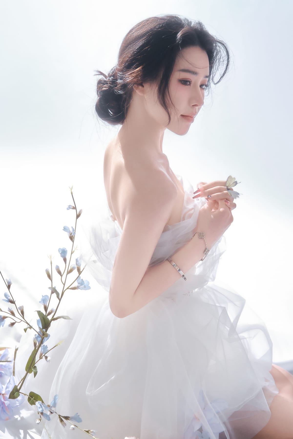 K9 Studio client portrait in a sheer white tulle dress, holding a butterfly, soft dreamy lighting